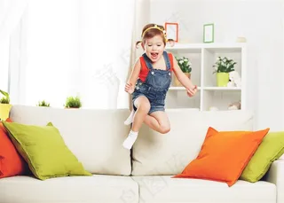 在沙发上跳跃的小女孩高清图片