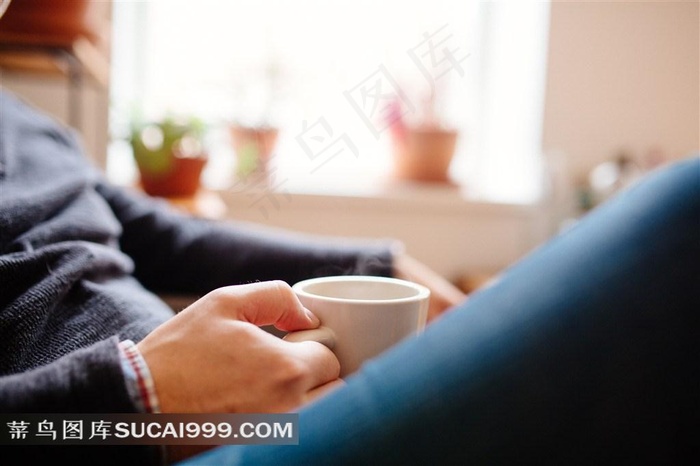 在房间里坐在椅子上手拿杯子的人