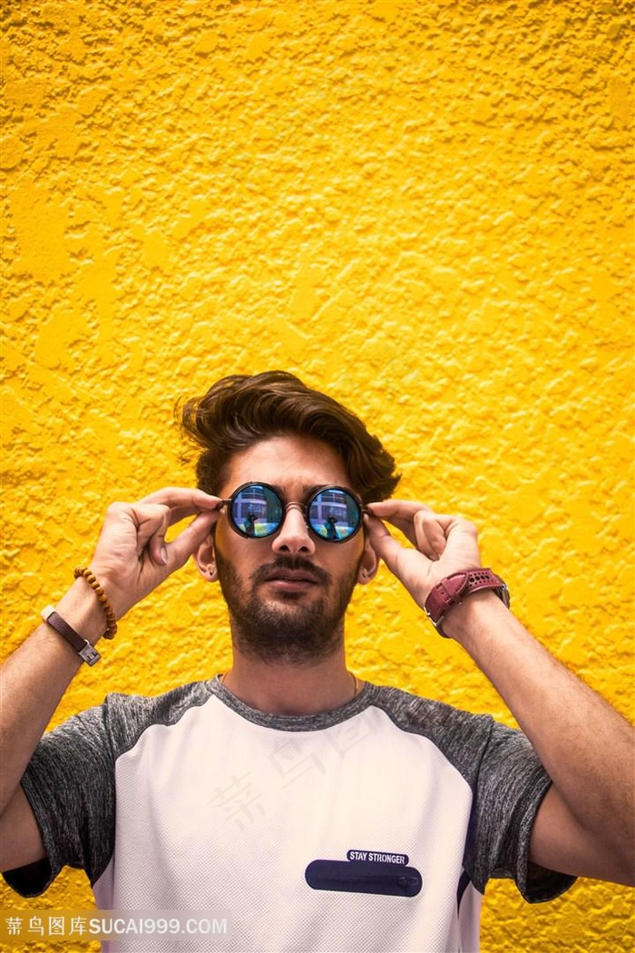 黄色背景墙前的墨镜帅哥