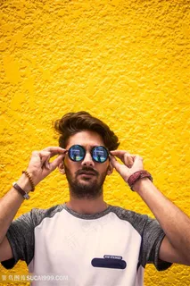 黄色背景墙前的墨镜帅哥