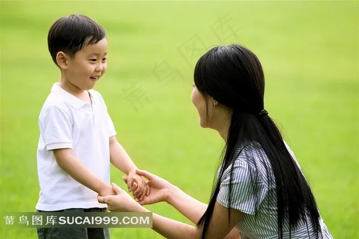 草地上拉手的母子摄影素材