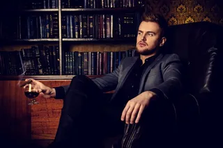 坐在黑色沙发上手拿红酒杯的外国男子高清摄影图片