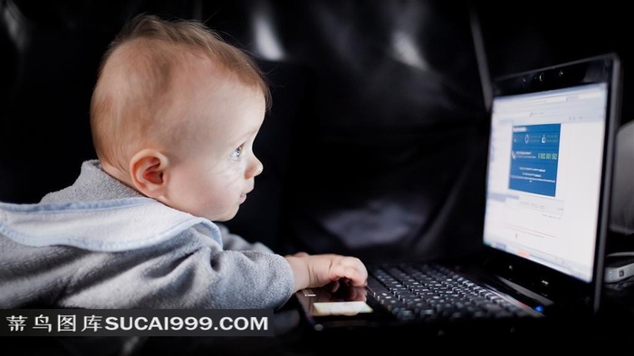 聚精会神玩弄电脑的小婴儿