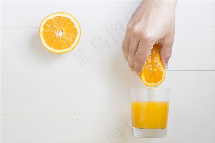 美味的用手把橙汁挤到玻璃杯里橙子与橙汁