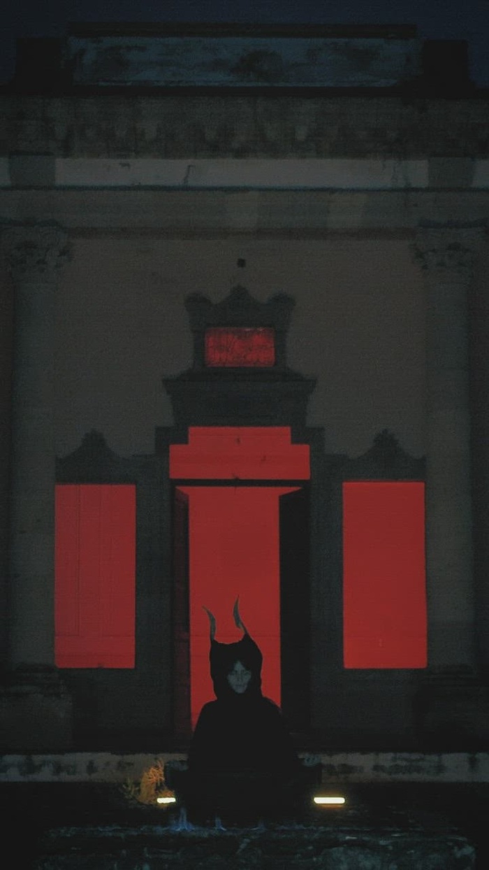 在一栋旧建筑前的黑暗中，有角的奇怪人