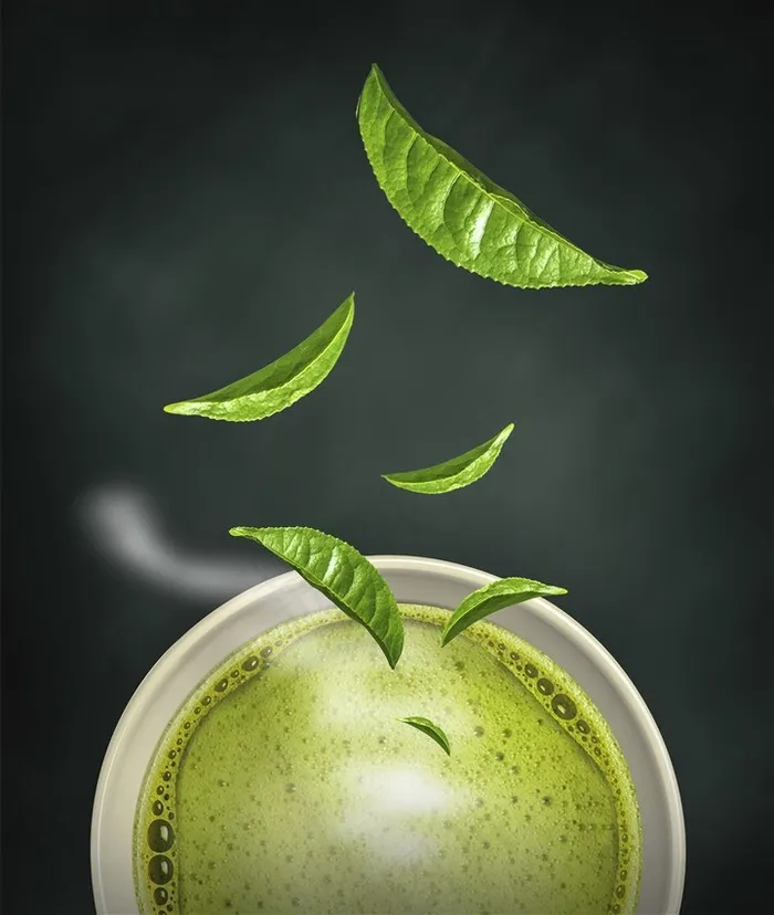 白色瓷杯里的抹茶饮料和飘落的茶叶高清图片