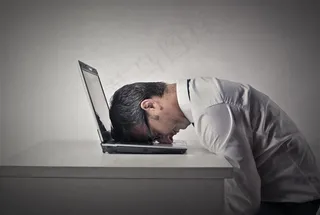 低头靠着笔记本键盘的员工高清摄影图片