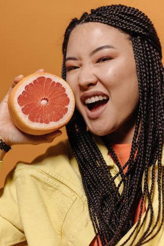 拿着柚子拍照的微笑女人图片