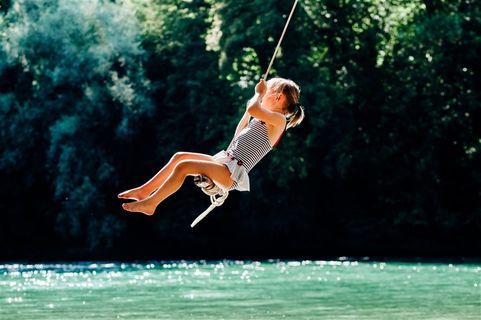 水面上空荡秋千的儿童摄影高清图片