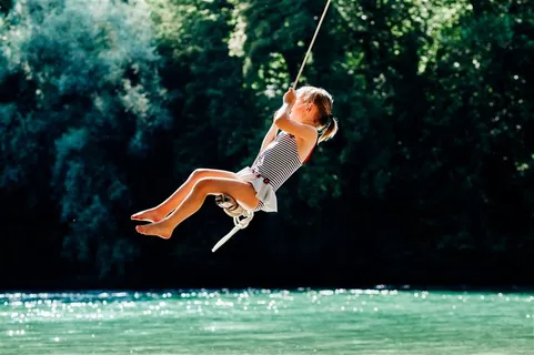 水面上空荡秋千的儿童摄影高清图片