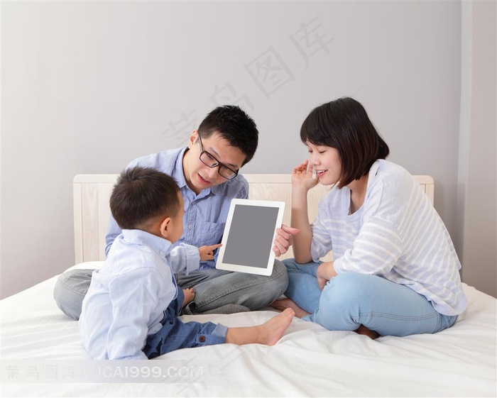 床上玩电脑的三口之家特写摄影高清图片
