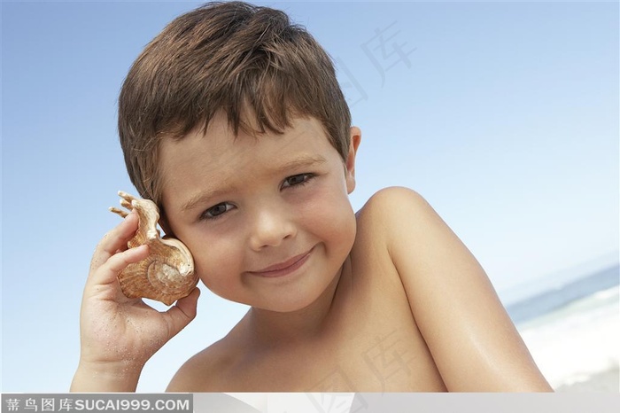 拿着海螺放在耳边听的外国小男孩
