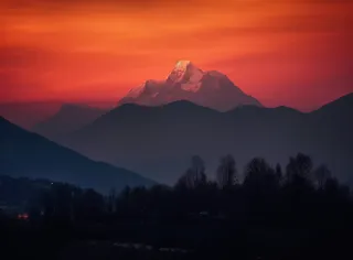 傍晚高原的山峰被落日照亮，日照金山风格摄影图
