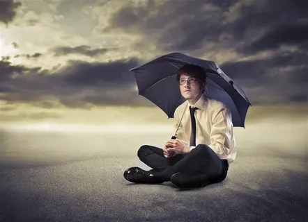 乌云下拿着伞的白领男人