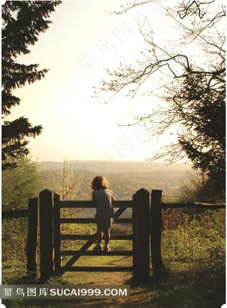 小孩趴在栅栏上看风景