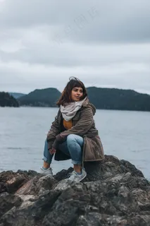 坐在海边礁石上的美女图片