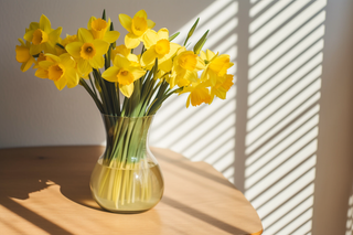 木桌上花瓶里养着的黄水仙鲜花摄影图