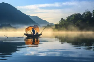 湖泊江河里的打渔船老伯摄影图