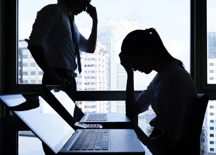 在电脑旁边手扶额头的一对男女高清摄影图片 在电脑旁边手扶额头的一对男女高清摄影图片