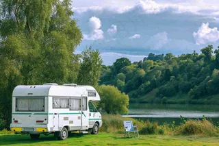野外露营湖边停着一辆房车，野餐，春游摄影图