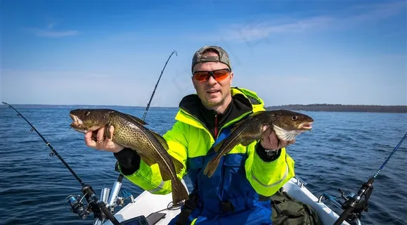 海上拿着两条鱼的男子高清摄影图