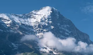 蓝天下雪山边的白色云雾