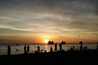 夕阳下海滩人群图片