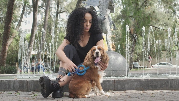 女孩和她的狗一起坐在喷泉旁