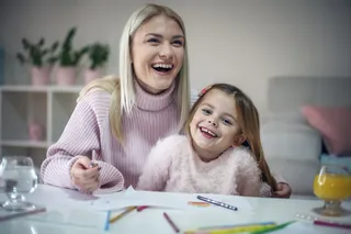 亲子互动母亲陪伴女儿画画绘画活动在开心的笑着