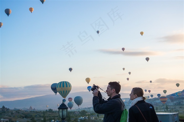 清晨观赏热气球升空的外国青年情侣