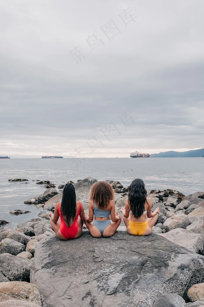 坐在大石头上冥想的女人背影图片