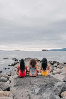 坐在大石头上冥想的女人背影图片