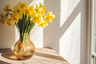 木桌上花瓶里养着的黄水仙鲜花摄影图