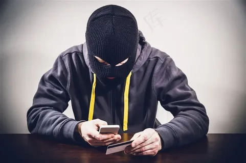 戴头套玩手机的男子高清摄影图