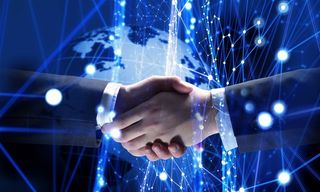 蓝色发光科技背景上握手的商务人士高清图
