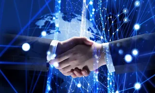 蓝色发光科技背景上握手的商务人士高清图