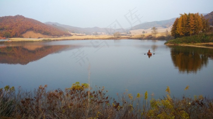 山脉间平静水面上划船的人