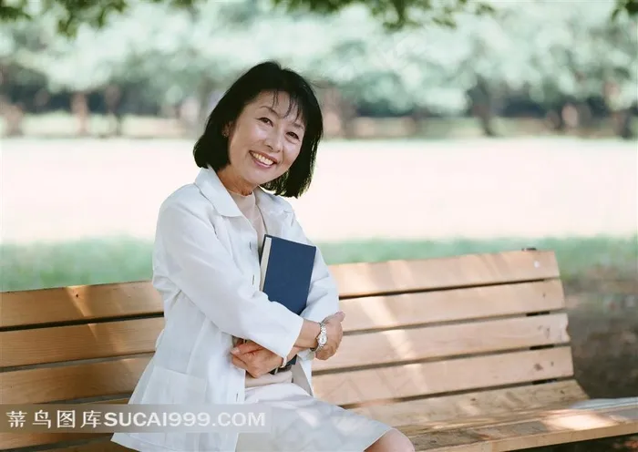 座椅上抱书微笑的女性老人