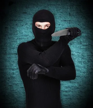 蓝色背景下挥舞匕首的黑衣男子