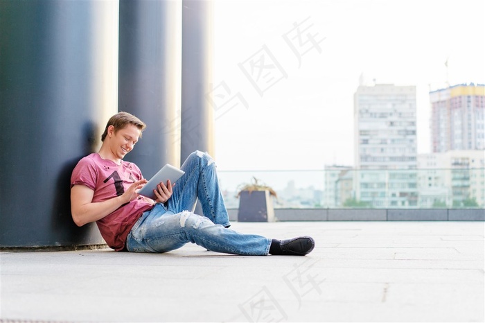 倚靠着水泥建筑坐着的男性高清图片