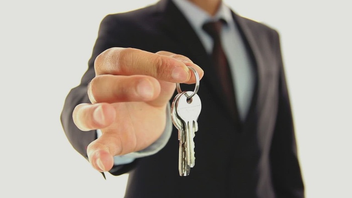 一个穿西装的男人把钥匙交给镜头