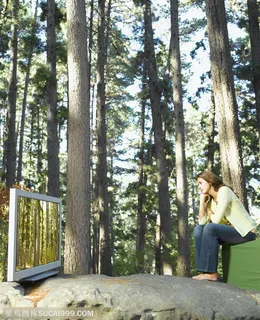 广告创意素材-坐在森林中观看电视的美女