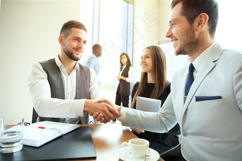 办公室里的工作人员和握手的商务人士高清图片