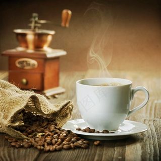 咖啡豆旁边冒着香气的白色咖啡高清摄影图片
