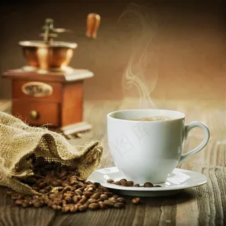 咖啡豆旁边冒着香气的白色咖啡高清摄影图片
