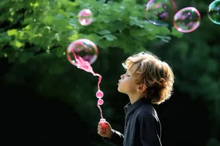 小孩吹泡泡玩耍绿叶背景