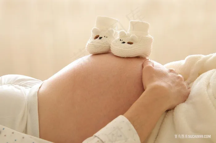 放在孕妇肚子上的婴儿鞋图片