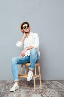 坐在木凳上戴着墨镜微笑的男士高清图片