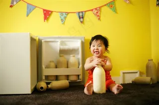 拿着牛奶罐大笑的可爱小女孩