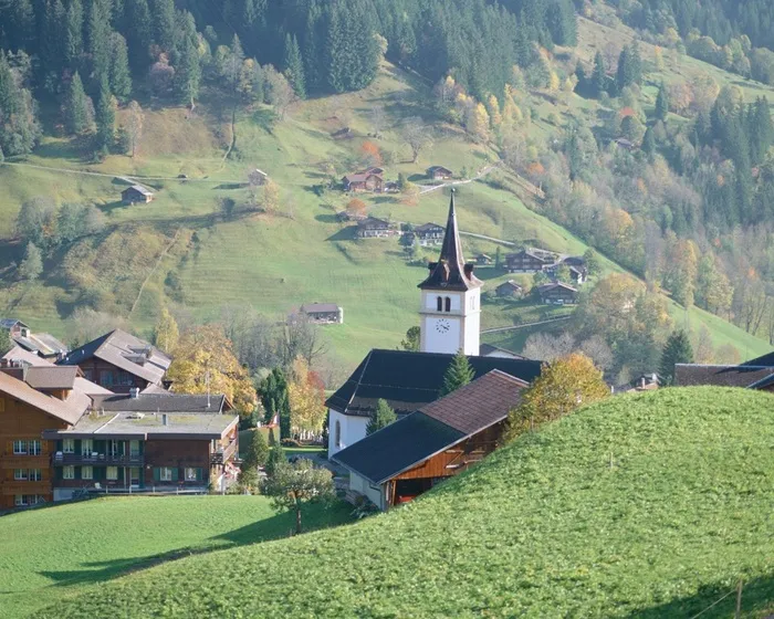 山脚下草地上的村庄风景图片